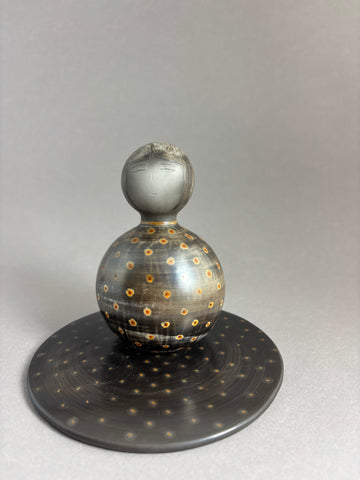 Kokeshi boule gris foncé aux pois colorés sur socle plat