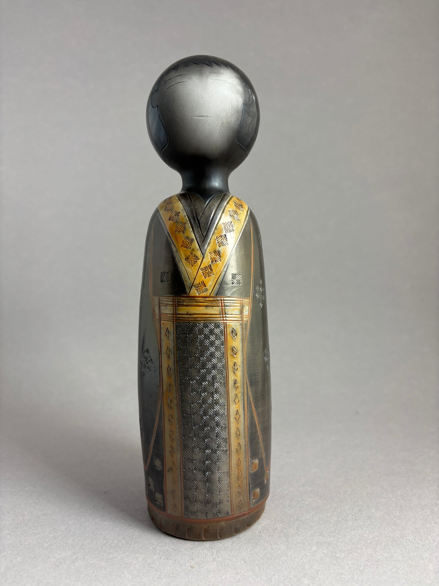 Kokeshi garçon kimono foncé petit motif répété donnant matière