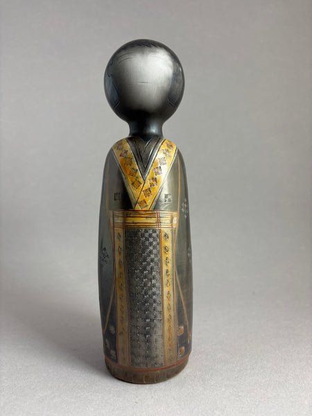 Kokeshi garçon kimono foncé petit motif répété donnant matière